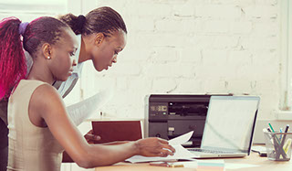 Two african business women working at laptop