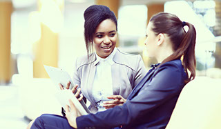 Two business woman sitting talking in an airport