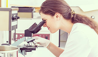 White woman scientist looking through microscope